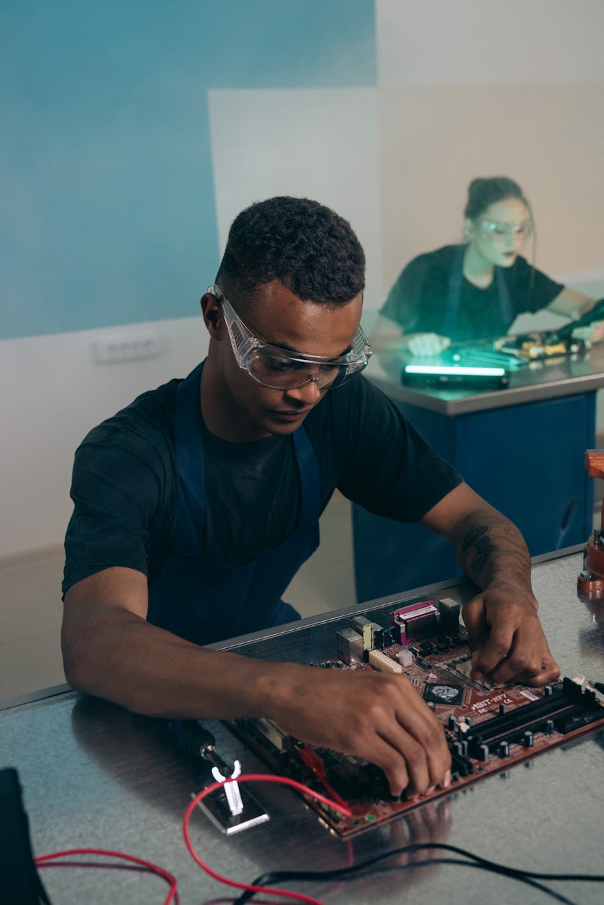 man in goggles sitting and working on computer hardware